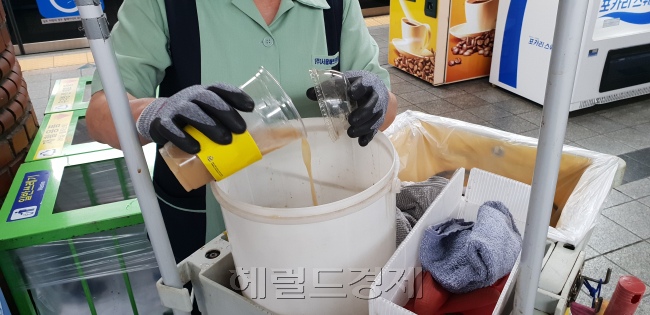 분리수거함 위에 버려져 있는 일회용 컵들(왼쪽사진). 환경미화원이 음료수컵에 남은 액체를 분리하고 있는 모습