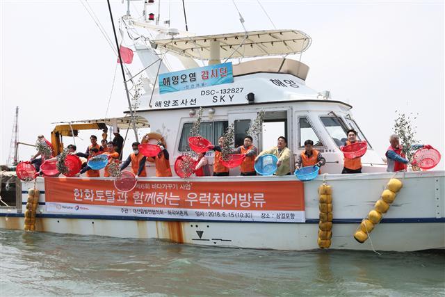 한화토탈 임직원과 대산지역 주민들이 지난 15일 진행한 바다가꾸기 행사에서 우럭과 광어 치어 33만여 마리를 대산 앞바다에 방류하고 있다.  [제공=한화토탈]