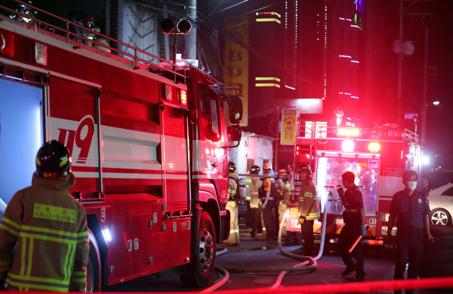 Police and firefighters examine the gutted bar in Gunsan, a city off South Korea's western coast on Monday, after a fire killed three customers and injured 30 others. Police suspected arson was the cause. (Yonhap)
