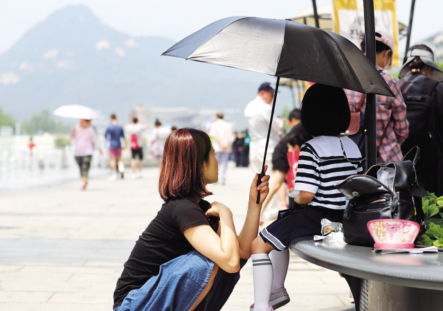 최근 들어 계속 지수가 나쁨 수준을 기록하고 있는 자외선은 자칫 피부암까지 유발할 수 있어 주의해야 한다. 자외선 지수가 ‘매우 나쁨’을 기록한 최근 서울 종로구 광화문광장에서 한 어머니가 딸에게 우산을 씌워 주고 있다.  [연합뉴스]