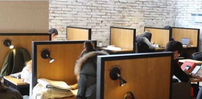 This file photo shows customers sitting at one-person tables at a cafe in Seoul. (Yonhap)