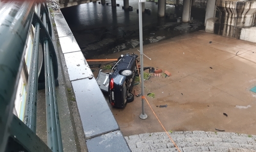 Car falls off Gosanja bridge into Cheonggyecheon on Friday. (Yonhap)