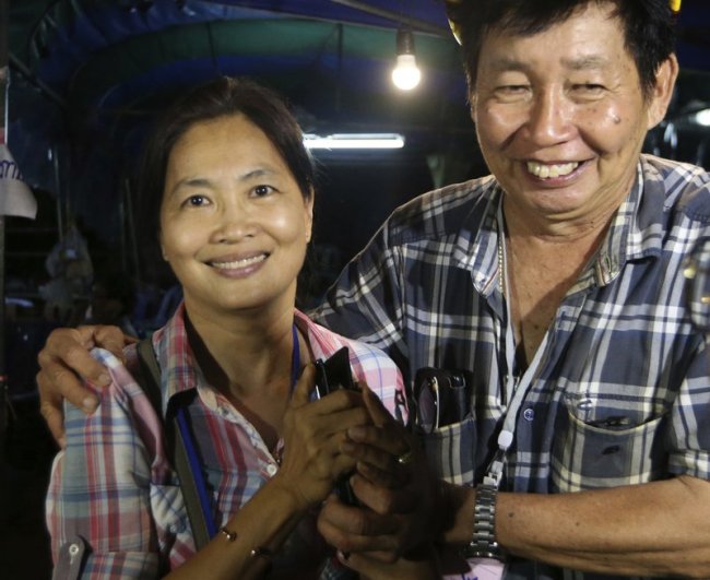 Family members smile after hearing the news that the missing 12 boys and their soccer coach have been found, in Mae Sai, Chiang Rai province, in northern Thailand, Monday, July 2, 2018. A Thai provincial governor says all 12 boys and their coach have been found alive in the cave where they went missing over a week ago in northern Thailand. (AP Photo)