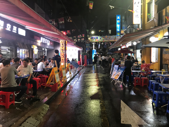 People sit outside in red plastic chairs in Euljiro Nogari Alley in downtown Seoul. (Yeo Jun-suk/The Korea Herald)