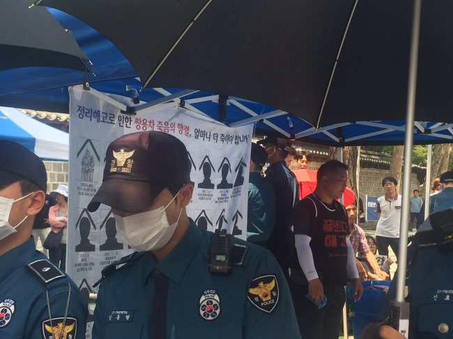 A mourner (third from right) stands still as elderly Koreans verbally attack him and his colleagues for setting up a memorial site for a late laid-off laborder who took his own life last month after suffering a long-term unemployment, in central Seoul on Wednesday. (Claire Lee/The Korea Herald)