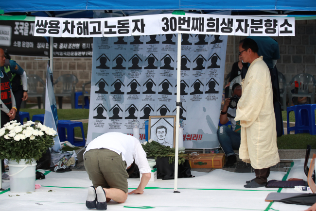 A citizen pays respect to the late Kim Ju-jung, a former Ssangyong Motors worker who took his own life after losing his job back in 2009. The tribute site was surrounded by conservative Koreans who insulted and physically attacked mourners. (Yonhap)