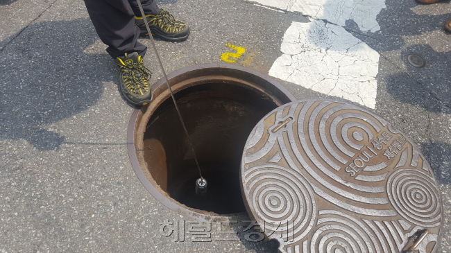 지난 4일 서울 용산구 주성동의 한 주택가에서 박문종 누수탐지전문관이 누수 감지기를 통해 땅 속 물이 새는 상수도관을 찾고 있는 모습(왼쪽)과 서울시 상수도사업본부 관계자가 맨홀 안을 살펴보고 있는 모습(가운데), 맨홀 안으로 누수 탐지기를 넣고 있는 모습(오른쪽). 이원율 기자/yul@