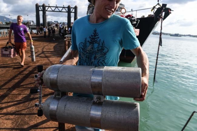 Divers carry oxygen tanks at Chalong pier in Phuket on July 7, 2018, as rescue operations continue for missing tourists following a boat accident on July 5. (AFP)