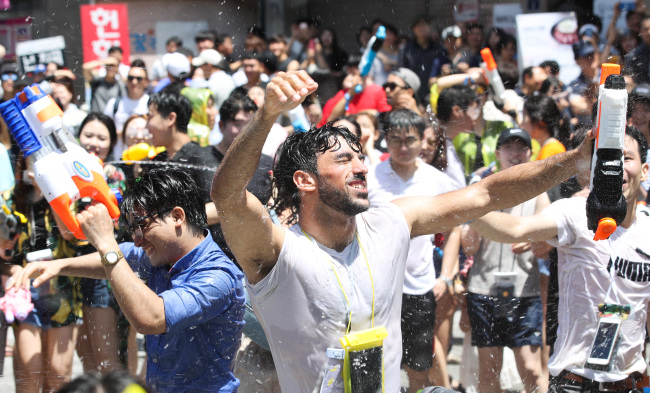 Crowds in raincoats firing water guns on Yonsei-ro during the 2018 Sinchon Water Gun Festival
