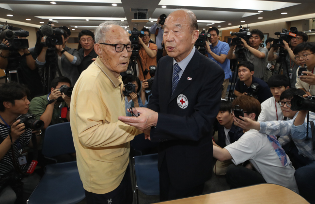 A family reunion candidate (left) holds hands with Korean Red Cross chief Park Kyung-seo at a meeting in Seoul on June 25. (Yonhap)