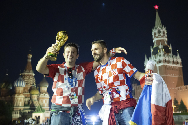 Croatia's soccer fans celebrate with a model of the World Cup trophy in Red Square as their team won the semifinal soccer match between Croatia and England during the 2018 soccer World Cup at the Luzhniki stadium in Moscow, Russia, early Thursday, July 12. (Yonhap)