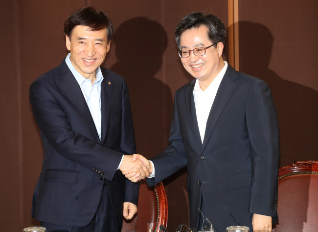 Finance Minister Kim Dong-yeon (R) shakes hands with Bank of Korea Gov. Lee Ju-yeol before holding a meeting in Seoul on July 16. (Yonhap)