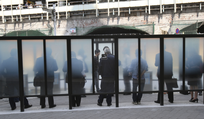 In this Friday, May 9, 2014, file photo, people smoke at a designated area in Tokyo. (AP)