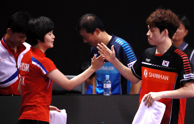 Players Cha Hyo-sim of North Korea (left) and Jang Woo-jin of South Korea (right) high-five each other at the International Table Tennis Federation World Tour Platinum Korea Open in Daejeon on Friday. Both are part of a unified Korean mixed double table tennis team. (Yonhap)