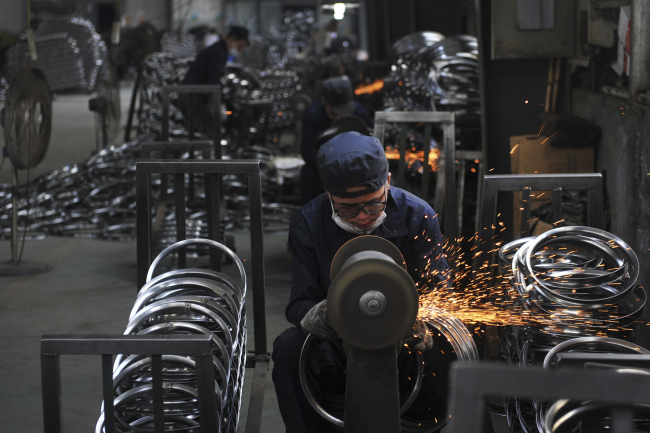 In this June 4, 2018, photo, a worker wields steel wheel rims at a factory in Hangzhou in east China's Zhejiang province.(Chinatopix via AP)