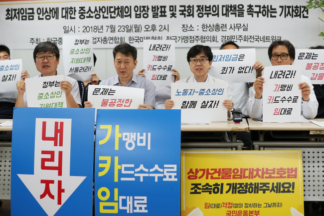 한국중소상인자영업자총연합회, 한국마트협회, 전국가맹점주협의회, 경제민주화전국네트워크 대표자들이 23일 오후 서울 영등포구 한국중소상인자영업자총연합회 사무실에서 열린 최저임금 인상 입장 발표 기자회견에서 손팻말을 들고 있다. 이들은 대기업ㆍ본사, 카드사, 임대인들이 물품대금에 최저임금 인상분 반영, 가맹비 및 필수물품 축소, 카드수수료 인하, 상가임대료 인하 등의 조치를 통한 고통분담에 나설 것과 국회가 상가임대차보호법, 카드수수료인하법, 가맹거래공정화 법안을 처리할 것, 정부가 중소상인들을 위한 추가적인 지원대책과 갑을구조 개혁을 위한 과제를 이행해줄 것을 촉구했다. (사진=연합뉴스)