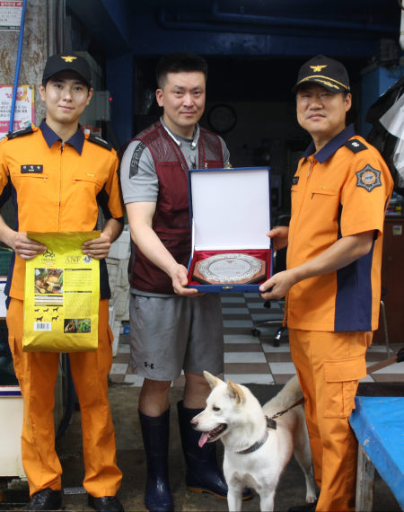 26일 오전 광주 북구 말바우시장에서 지난 22일 시장 내에서 화재가 발생하자 짖어 알린 견공에게 광주 북부소방서 대원들이 표창장을 수여하고 있다. [사진=광주 북부소방서/연합뉴스]