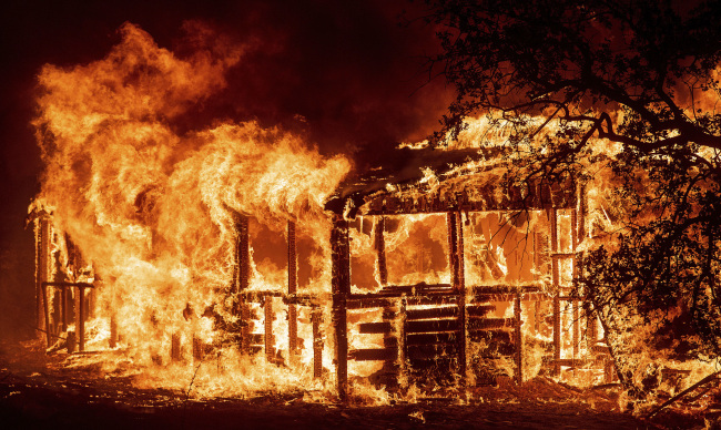 In this Thursday, July 26, 2018 file photo, a structure burns as the Carr fire races along Highway 299 near Redding, California. (AP-Yonhap)