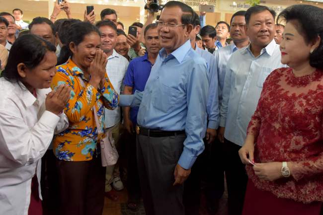 Cambodia's Prime Minister and leader of the ruling Cambodian People's Party (CPP) Hun Sen (center) and his wife Bun Rany (right) greet people during general elections at a polling station in Kandal province, outside of Phnom Penh, on Sunday. (AFP via Yonhap)