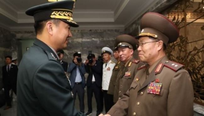 This photo, provided by Seoul's defense ministry, shows South Korea's top delegate Major Gen. Kim Do-gyun (L) shaking hands with his North Korean counterpart Lt. Gen. An Ik-san before starting their first general-level talks in more than 10 years at the truce village of Panmunjom on June 14. (Yonhap)