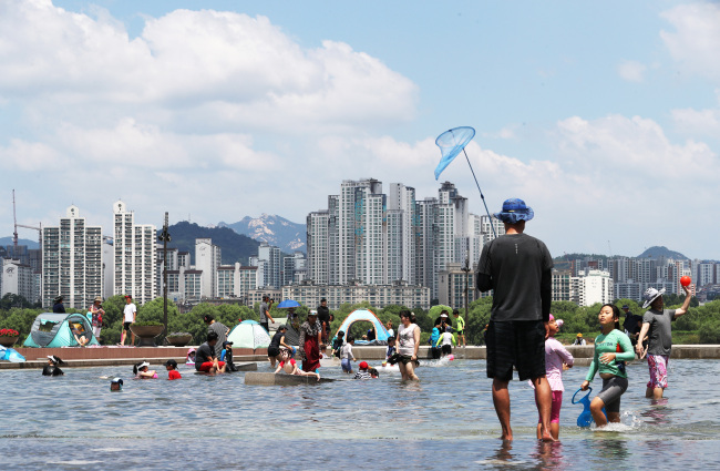 Children play with water near the Han River in Yeouido, Seoul, Sunday.