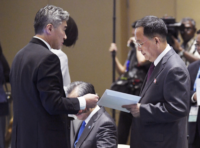 North Korean Foreign Minister Ri Yong-ho, right, receives an envelope from US Ambassador to the Philippines Sung Kim before the start of the 51st ASEAN Foreign Ministers Meeting in Singapore, Saturday, Aug. 4, 2018. (AP-Yonhap)