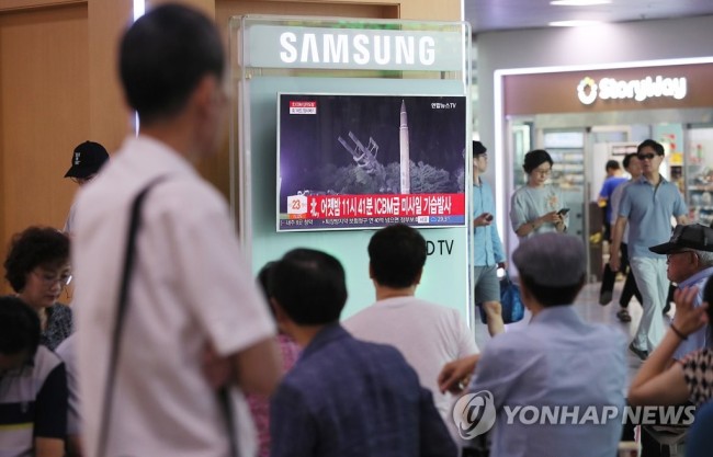 This undated photo shows South Koreans watch TV reports on (Yonhap)