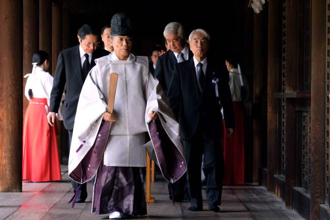 Japanese lawmakers follow a Shinto priest (center) after performing a ritual for the war dead on the 73rd anniversary of Japan's surrender in World War II, at the controversial Yasukuni shrine in Tokyo on August 15, 2018. Japan's Emperor Akihito on August 15 expressed "deep remorse" about his nation's wartime acts, as Tokyo marked the 73rd anniversary of the end of World War II. (AFP)