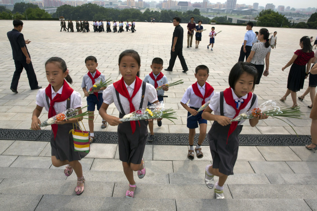 Children hold flowers as they pay their respects before the giant bronze statues of late North Korean leaders Kim Il Sung and his son Kim Jong Il during the anniversary of the end of World War II and liberation from Japanese colonial rule in Pyongyang, North Korea on Wednesday, Aug. 15, 2018. (AP)