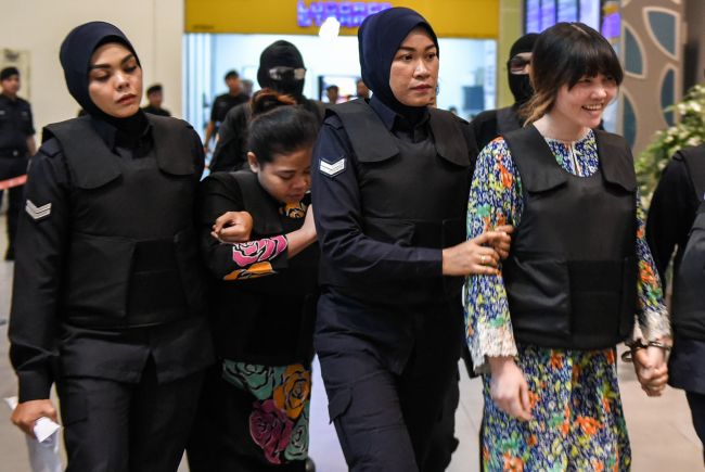This file photo taken on October 24, 2017 Vietnamese defendant Doan Thi Huong (R) and Indonesian defendant Siti Aishah (2nd L) are escorted by Malaysian police personnel at the low-cost carrier Kuala Lumpur International Airport 2 in Sepang during a visit to the scene of the murder as part of the Shah Alam High Court trial process for their alleged role in the assassination of Kim Jong-Nam. (AFP)