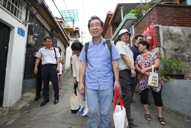 Seoul Mayor Park Won-soon (center) leaves his temporary residence -- a humble rooftop dwelling without air-conditioning -- in Samyang-dong, northern Seoul, Sunday. (Yonhap)