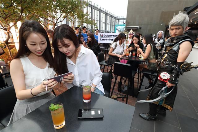 지난 20일 노보텔 앰배서더 서울 동대문에서 열린 KT의 ‘갤럭시노트9’ 사전개통 기념 행사에서 참석자들이 갤노트9을 체험하고 있다.[제공=KT]  (오른쪽)21일 서울 을지로 SK텔레콤 본사 T타워에서 열린 ‘갤럭시노트9’ 사전개통 행사에서 방송인 김준현, 유민상, 김민경, 문세윤이 참석자들과 기념사진을 찍고 있다. 이날 행사에는 참석자들이 ‘T플랜’의 넉넉한 데이터를 상징하는 지름 60㎝ 대형 피자를 나눠먹는 시간을 가졌다.
[제공=SK텔레콤]