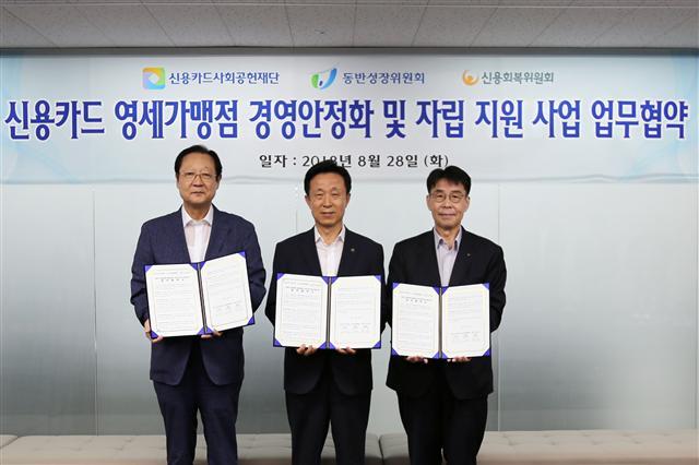 권기홍 동반성장위원회 위원장(왼쪽부터), 김덕수 신용카드사회공헌재단 이사장, 김윤영 신용회복위원회 위원장이 영세가맹점 자립 지원 협약서를 들어보이고 있다.