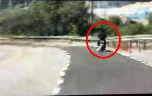 A man on a motorcycle drags a dog by its leash. (Yonhap)