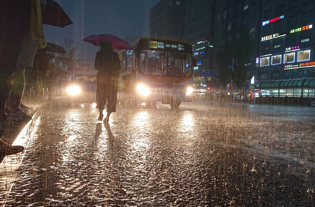 A commuter waits for a bus in Goyang, Gyeonggi Province on Tuesday in torrential rain.(Yonhap)
