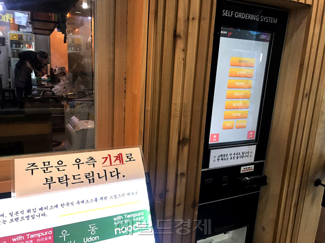 서울 마포구 한 덮밥집 입구. ‘주문은 모두 우측 기계로 부탁드립니다’라는 표시와 함께 키오스크가 설치돼 있다. 영세 자영업자들은 최저임금의 급격한 인상 후 렌털식 키오스크를 도입해 인건비 줄이기에 사활을 걸고 있다. [사진=김지윤 기자]