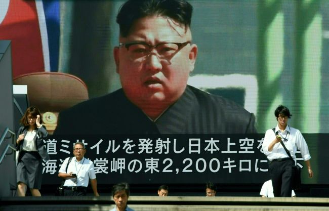 In this file photo taken on September 15, 2017, pedestrians walk in front of a large video screen in Tokyo broadcasting a news report showing North Korean leader Kim Jong-Un, following a North Korean missile test that passed over Japan. (AFP-Yonhap)