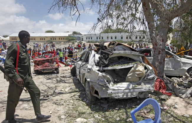 A Somali soldier walks near the wreckage of vehicles at the scene of a blast outside the compound of a district headquarters in the capital Mogadishu, Somalia Sunday, Sept. 2, 2018. (AP-Yonhap)
