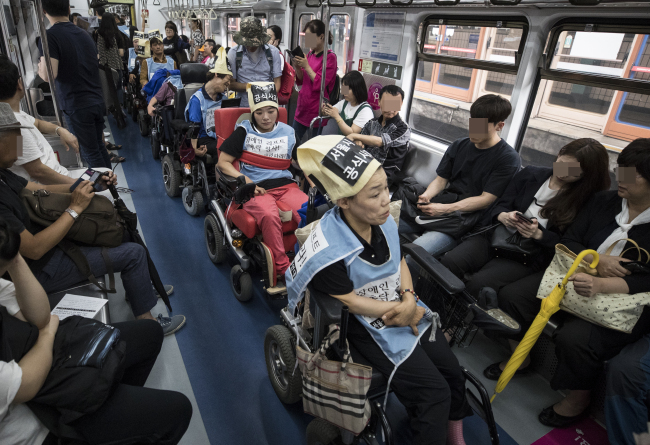 South Koreans with disabilities protest Seoul's public transportation system, which they claim to be unsafe and non-inclusive, inside a Seoul Metro train in July (Yonhap)