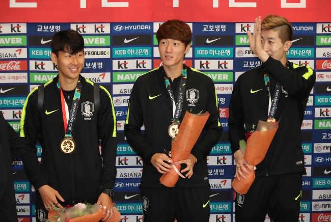South Korean soccer players Son Heong-min(left), Hwang ui-jo(center) and Jo Hyeon-woo wave to the crowd of fans at incheon airport on Monday. Yonhap