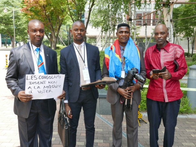 Bwelungu Nombi Henry (left), a Congolese activist living in South Korea, protests against Miru Systems, a Korean firm that has signed a deal to supply its controversial voting devices to Congo`s upcoming election in December, in Pangyo, Gyeonggi Province, on July 16. (Claire Lee/ The Korea Herald)