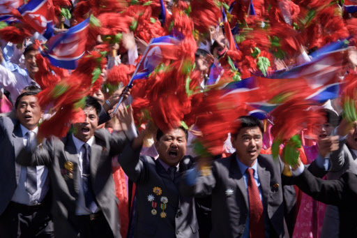 Participants wave flowers as they march past a balcony from where North Korea's leader Kim Jong Un was watching, during a mass rally on Kim Il Sung square in Pyongyang on September 9, 2018. - North Korea held a military parade to mark its 70th birthday, but refrained from showing off the intercontinental ballistic missiles that have seen it hit with multiple international sanctions. (AFP)