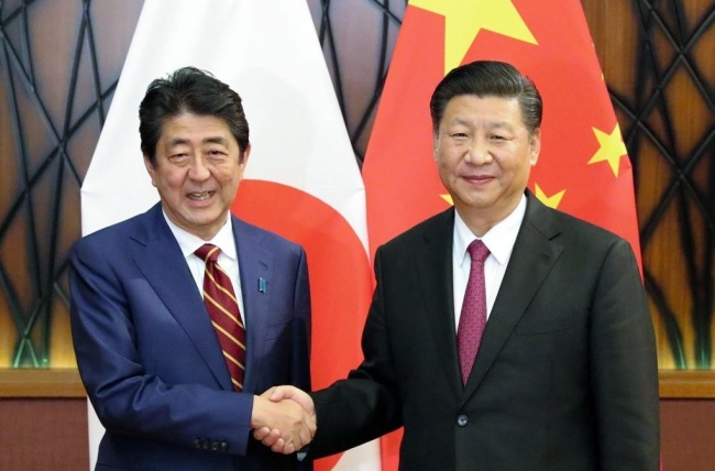 Japanese Peime Minister Shinzo Abe, left, shakes hands with Chinese President Xi Jinping, right. (Yonhap)