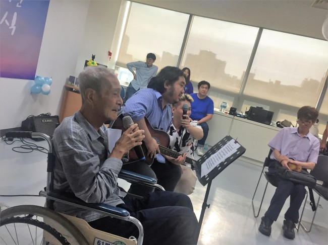 Kim Byung-guk (in wheelchair) sings his all-time favorite song, along with a group of young social activists, at his funeral at Seoul Metropolitan Dongbu Hospital on Aug. 14. (Claire Lee/ The Korea Herald)