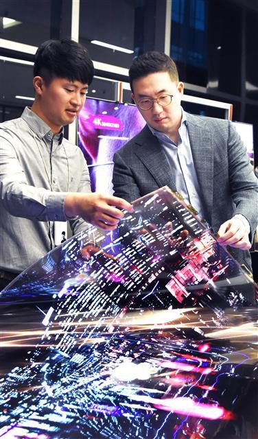 구광모 LG 회장이 지난 12일 LG사이언스파크를 방문해 연구원과 함께 ‘투명 플렉시블 OLED’를 살펴보고 있다.  [제공=LG]