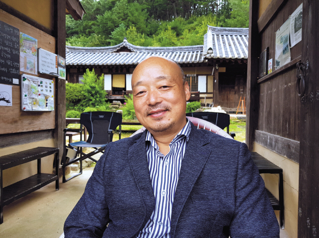 낙동강이 내려다 보이는 시례예술촌 대문에 앉아 미소짓는 이희오 대표
