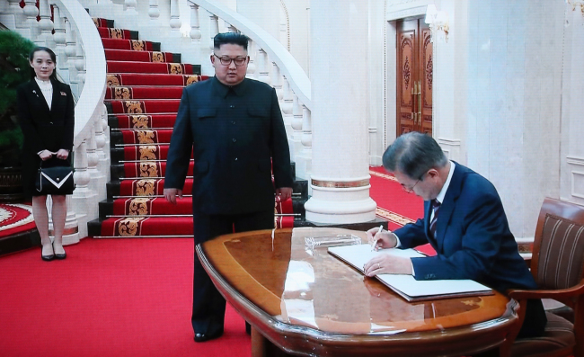 North Korean leader Kim Jong-un stands by a desk while Moon Jae-in writes his name on the visitors‘ log at the headquarters of the Central Committee of the Workers’ Party of Korea in Pyongyang on Tuesday, ahead of their summit.  / Joint Press Corp.