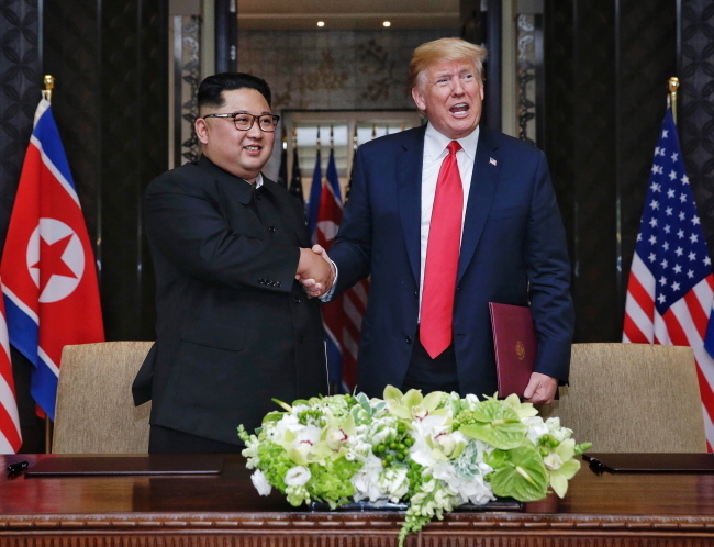 US President Donald Trump (R) and North Korean Chairmain Kim Jong-un (L) shake hands after signing a document during their historic DPRK-US summit (Yonhap)