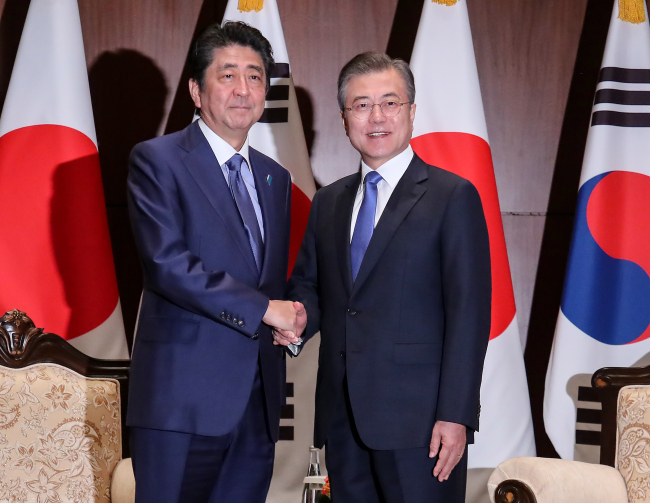 South Korean President Moon Jae-in (R) and Japanese Prime Minister Shinzo Abe shake hands before the start of a bilateral summit held in New York on Sept. 25. (Yonhap)
