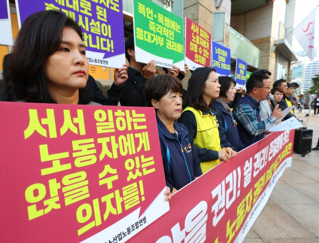 Unionized workers in Korea's service sector hold signs that read "Give chairs to workers" at a rally in Seoul. (Yonhap)